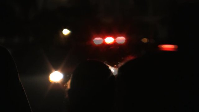 People stand back at a crime scene with a police cars flashing lights. HD 1080.