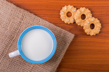 Cup of milk with cookies on wooden table - top view