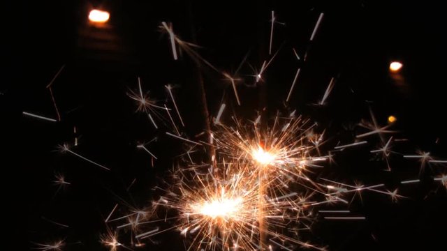 Two sparklers in a persons hand shooting sparks. HD 1080p.