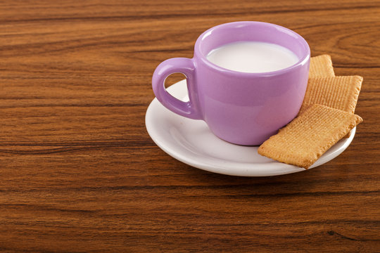 Cup of milk with cookies on wooden table