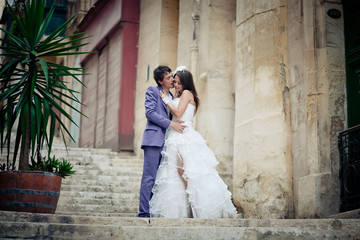 Groom holds bride's waist tender while kissing her on yellow foo