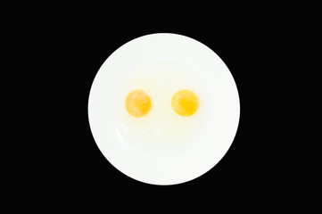 Raw egg yolks in a white bowl isolated on a black background, To prepare for a high protein diet has helped in the growth of a person's body