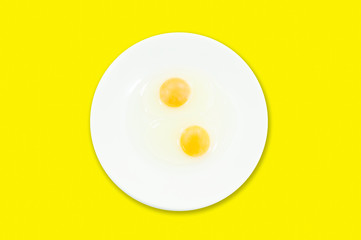 Raw egg yolks in a white bowl isolated on a yellow background, To prepare for a high protein diet has helped in the growth of a person's body