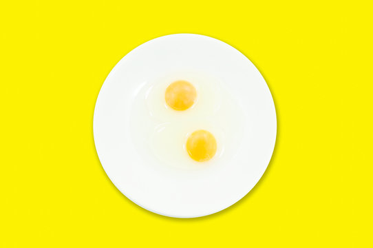 Raw egg yolks in a white bowl isolated on a yellow background, To prepare for a high protein diet has helped in the growth of a person's body