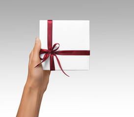 Isolated Woman Hands holding Holiday Present White Box with Red Ribbon on a White Background