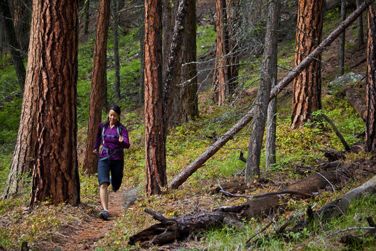 A young asian woman trail running in the 3 Blind Mice trail system. Penticton, BC