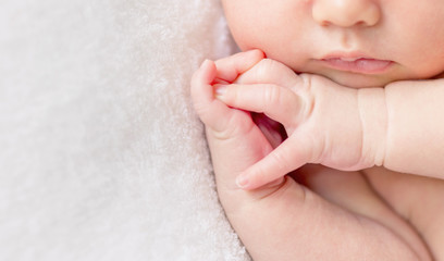 crossed fingers of a newborn baby asleep, closeup - obrazy, fototapety, plakaty
