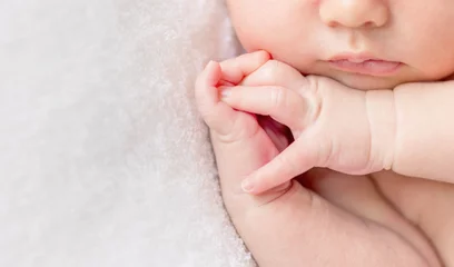 Fototapeten crossed fingers of a newborn baby asleep, closeup © tan4ikk