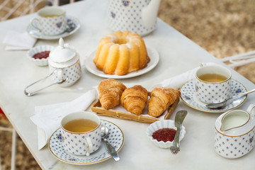 Tazas de té infusión con croissant y bizcocho sobre una mesa. Vista superior. Desayuno al aire libre. La hora del té