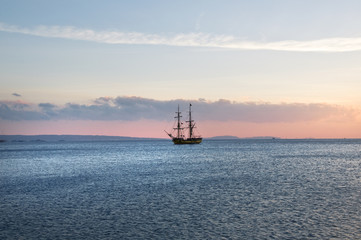 sailing ship at anchor, a blue calm sea and cloudless sky