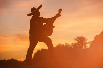 Mexican, Latin American, Spanish. Musician on the coast. Silhouette at sunset.