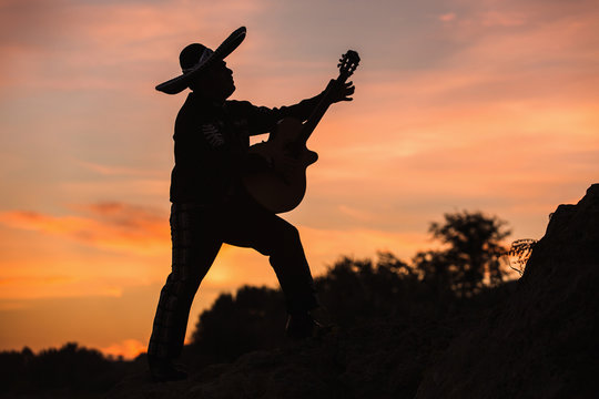 Mexican, Latin American, Spanish. Musician on the coast. Silhouette at sunset.