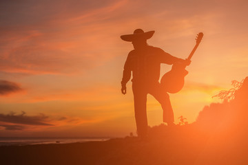 Fototapeta na wymiar Mexican musician mariachi on the coast. Silhouette at sunset.