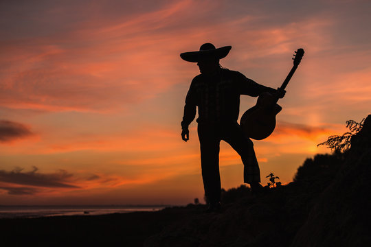 Mexican, Latin American, Spanish. Musician on the coast. Silhouette at sunset.