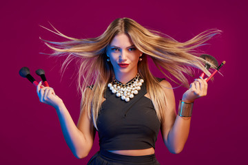 Naklejka premium Female stylist with hair flying holding makeup brushes