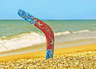 Boomerang on Sandy Beach Against of Azure Sea Surf.