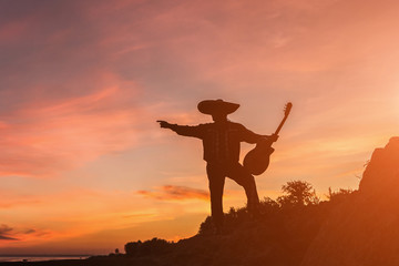 Mexican, Latin American, Spanish. Musician on the coast. Silhouette at sunset.