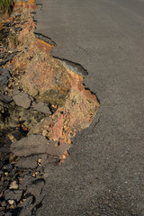 Side of the broken asphalt road collapsed and fallen