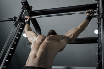 Entrenando en el gimnasio. Hombre con grandes músculos levantando peso mientras entrena en el...