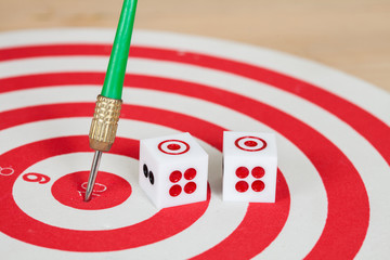 Dice on dart board with green dart arrow