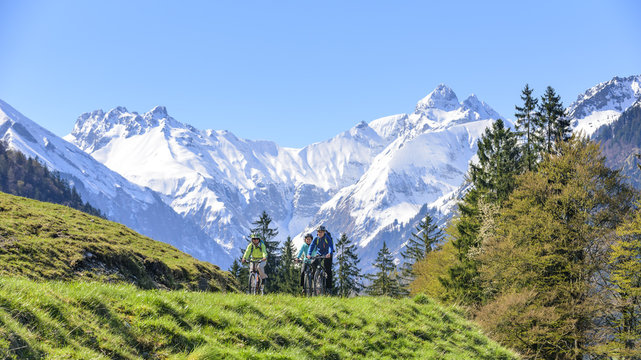 Drei Radfahrer im Allgäu vor frisch verschneiten Bergen