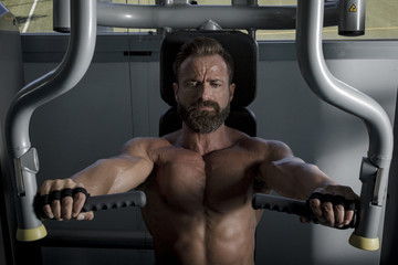 Entrenando en el gimnasio. Hombre con grandes músculos levantando peso mientras entrena en el...