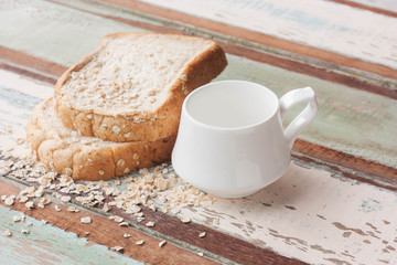 Bread and coffee cup on wood background.