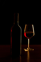 Red wine bottle with glass on black background - silhouette