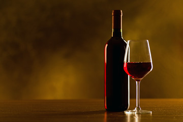 Red wine bottle with glass on black background
