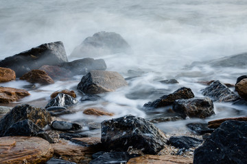 long exposure of misty sea and rocks on the beach.