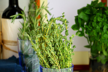 Fresh green thyme against kitchen background with bottles of wine and italian herbs