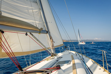 Sailing boat going fast on she's sails, view from the cockpit to bow.