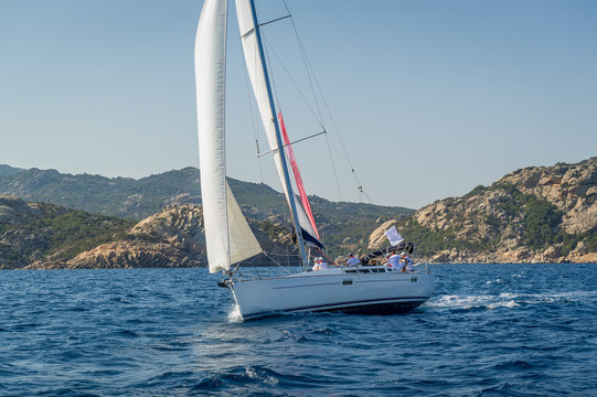 Cruising sailboat sailing near Sardinia island shores.