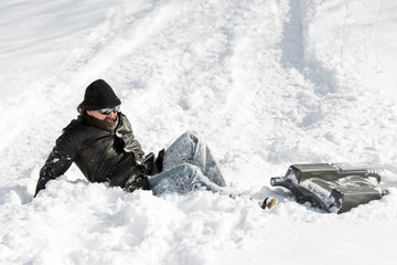Mann liegt im tiefen Schnee, Schlitten daneben