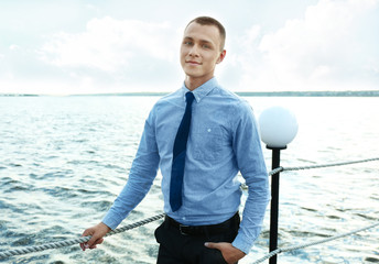 Man in blue shirt and black leather tie on a pier