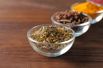 Assortment of spices in glass bowls on wooden background