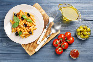 Delicious penne pasta with ingredients on wooden table