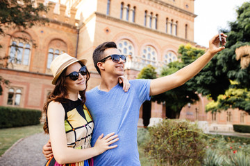 Fototapeta na wymiar Happy couple of tourists taking selfie in old city