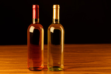 Fototapeta na wymiar Rose and white wine bottles on wooden table and black background