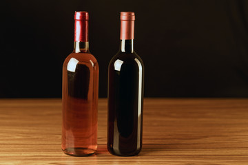 Fototapeta na wymiar Rose and black wine bottles on wooden table and black background