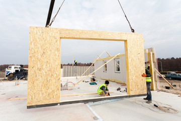 Roofer builder worker with crane installing structural Insulated Panels SIP. Building new frame...