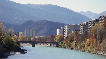 Colorful day at the Inn river with the sun shinning at the autumn colored trees and the green river water