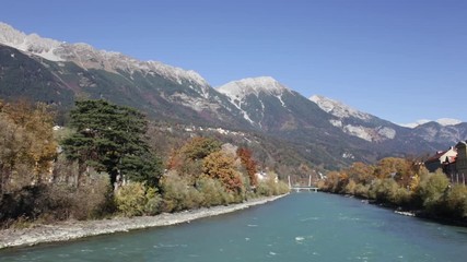 Colorful day at the Inn river with the sun shinning at the autumn colored trees and the green river water