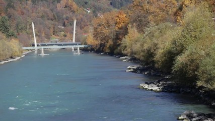 Colorful day at the Inn river with the sun shinning at the autumn colored trees and the green river water