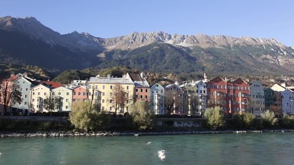 Colored houses by the Inn river with the mountains in the background at Mariahilfstrasse in Innsbruck, Austria