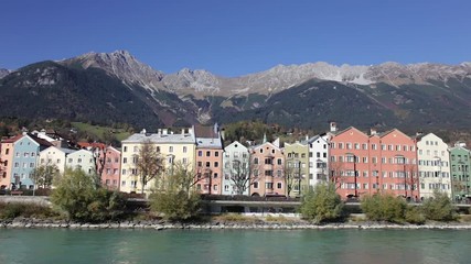 Colored houses by the Inn river with the mountains in the background at Mariahilfstrasse in Innsbruck, Austria