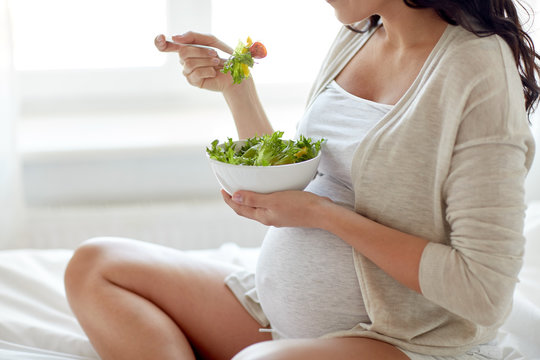 close up of pregnant woman eating salad at home