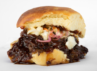 Smoked meat beef sandwich, with barbecue sauce and coleslaw isolated on a white background.