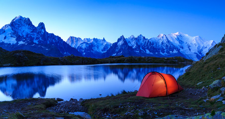 Red tent at Lac De Chéserys in the mountains near Chamonix, France, during sunrise.