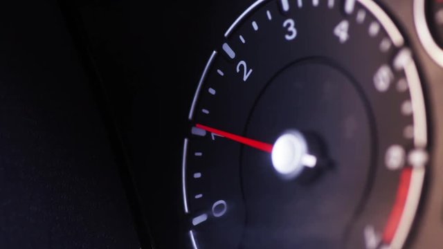 Color close up footage of a car's tachometer idling.